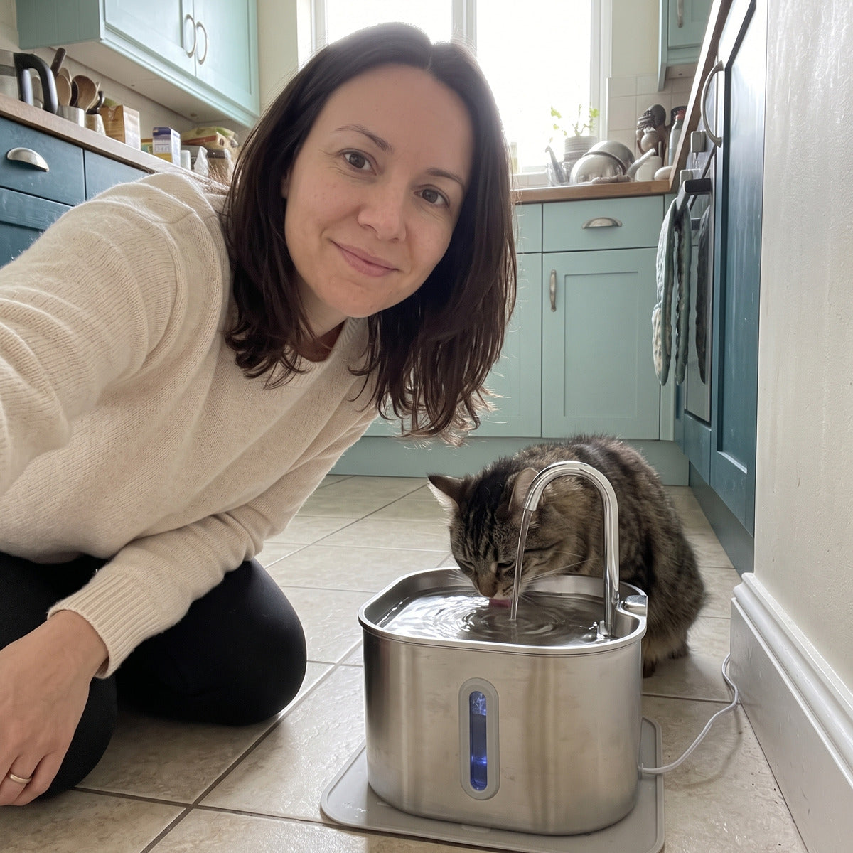 Owner selfie beside a cat fountain in a kitchen